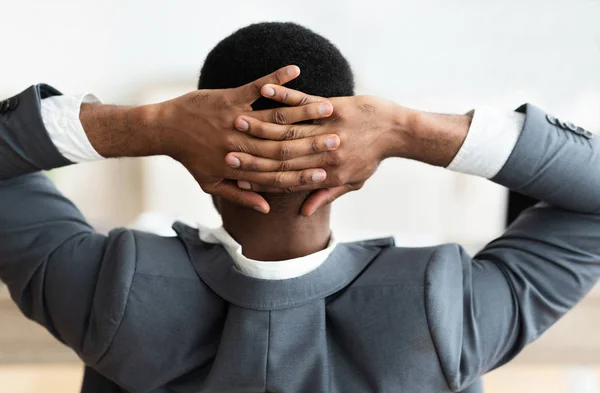 Hombre de negocios negro cansado cruzando las manos detrás de la cabeza, estirándose hacia atrás —  Fotos de Stock