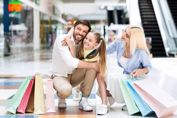 Pais e filha sentados em assombrações e abraços no shopping — Fotografia de Stock