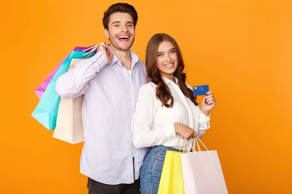 Casal atraente com sacos de compras e cartão de crédito — Fotografia de Stock