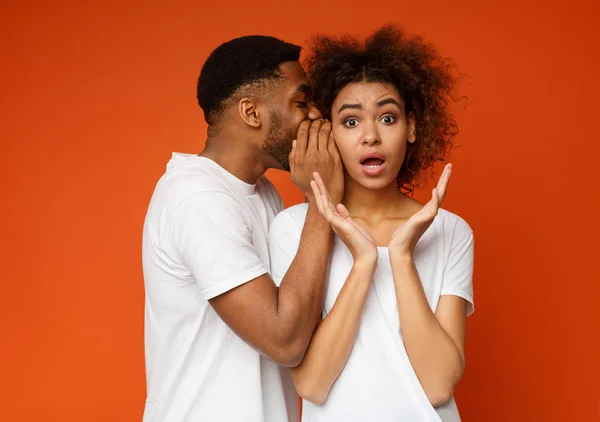 Africano americano homem sussurrando para chocado namorada — Fotografia de Stock