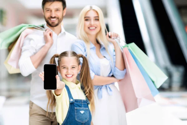 Família feliz mostrando tela do telefone em pé no shopping, Mockup — Fotografia de Stock