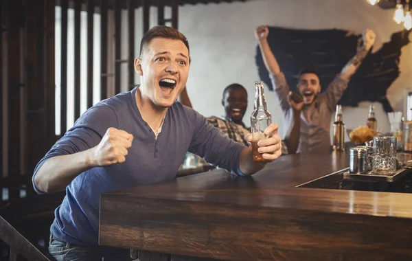 Emocionado fanático del fútbol viendo el partido en el bar, bebiendo cerveza — Foto de Stock