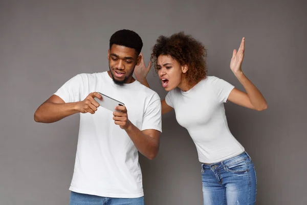 Black man playing on cellphone, his girlfriend screaming for ignoring her — Stock Photo, Image