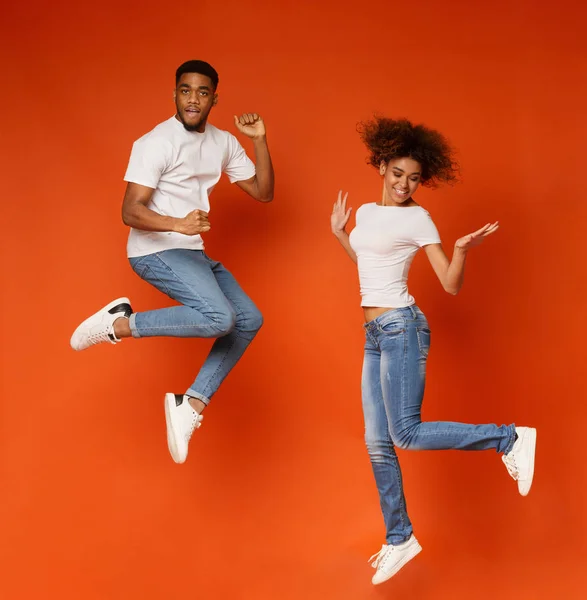 Carefree african american man and woman jumping in air — Stock Photo, Image