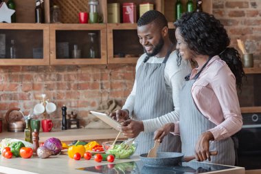 Yemek pişirirken dijital tablet kullanan sevimli çift