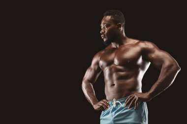 Seksi kas fitness modeli siyah arka plan üzerinde vücudunu gösteren