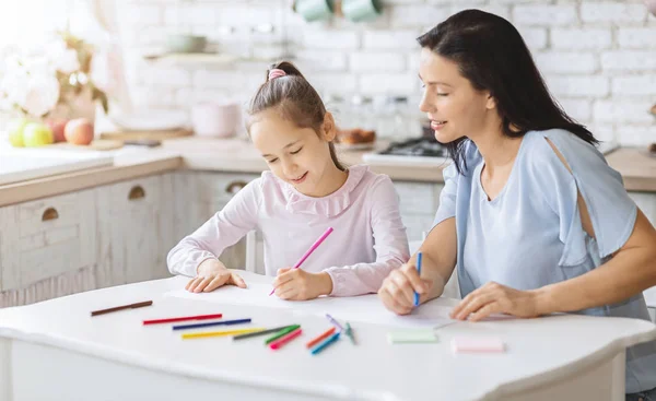 Mère dessine avec sa fille sur la table de cuisine — Photo