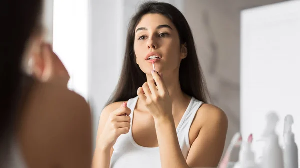갈색 머리 여자 적용 립스틱 에 앞 의 거울 에 욕실 — 스톡 사진