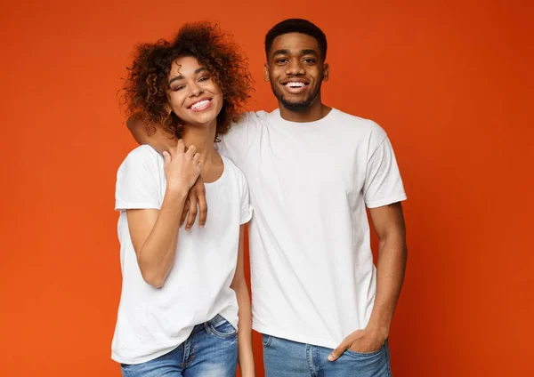 Glückliche afrikanische Millennials umarmen sich auf orangefarbenem Hintergrund — Stockfoto