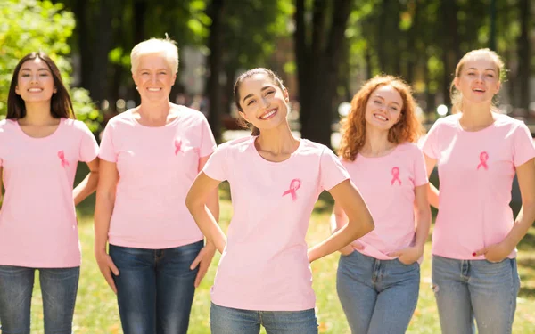 Donne in t-shirt con nastri di consapevolezza rosa in piedi nel parco — Foto Stock