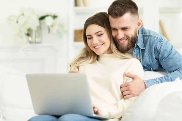 Красива молода пара розслабляється у вітальні і використовує ноутбук — стокове фото