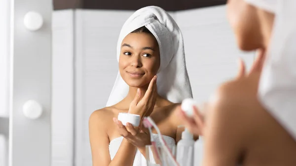 Afro Young Lady aplicando crema facial de pie en el baño, Panorama — Foto de Stock