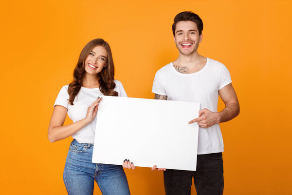 Happy man and woman posing with white empty board