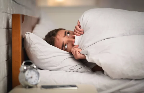 Dívka ležící v posteli tahá deku přes obličej doma — Stock fotografie