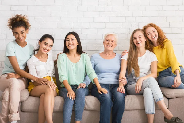 Grupo de mujeres sonriendo sentadas en un sofá contra la pared blanca — Foto de Stock