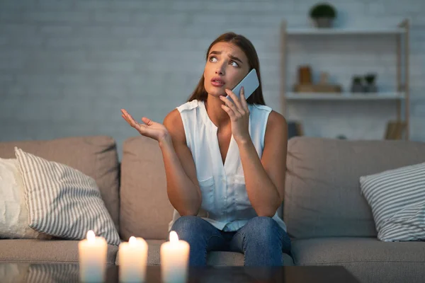 Flicka ringer elektriker service sitter på soffan i mörkt rum — Stockfoto
