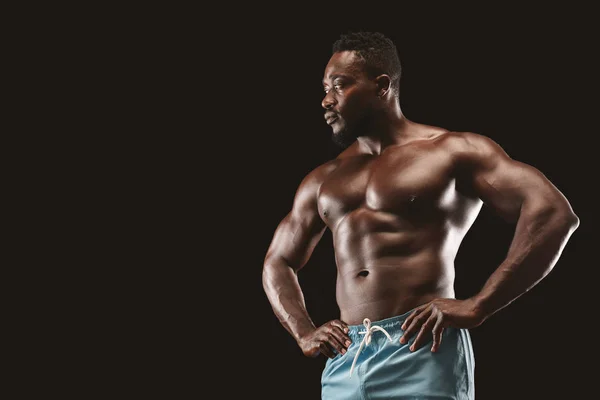 Sexy muskulární fitness model zobrazující jeho tělo na černém pozadí — Stock fotografie