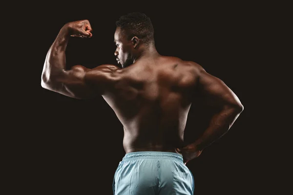 Forte fisiculturista afro demonstrando seu bíceps muscular — Fotografia de Stock