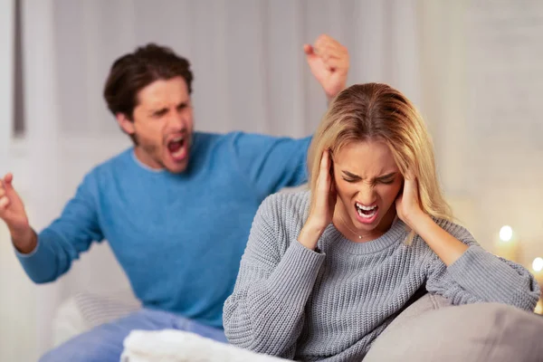 Agresivo hombre gritando a novia sentado en sofá en casa —  Fotos de Stock