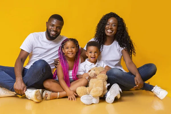 Retrato de familia feliz con dos hijos sobre fondo amarillo — Foto de Stock