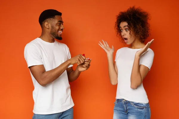 Shocked african woman looking at her boyfriend with engagement ring — Stock Photo, Image