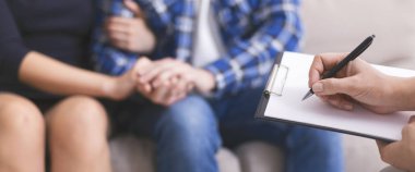 Endişeli çift el ele tutuşuyor, not defterinde uzman yazma raporu