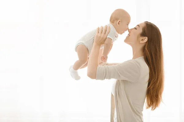 Madre tocando narices con su bebé mientras lo levanta — Foto de Stock