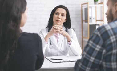 Kadın hekim konsültasyon sırasında hastalarını dinliyor