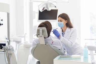Genç kadın diş hekimi hastaya tedavi yapıyor