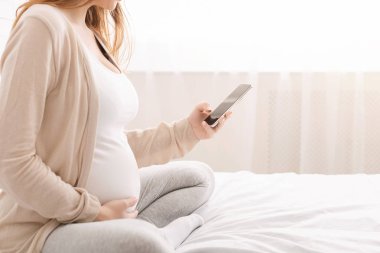 Hamile kadın cep telefonu yla ağ, yatakta oturan