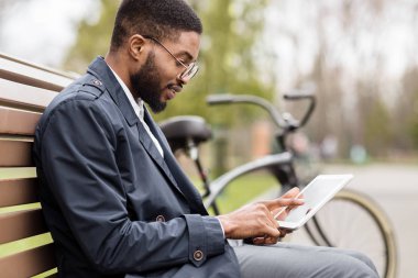 Afro işadamı mola ve parkta tablet kullanarak sahip