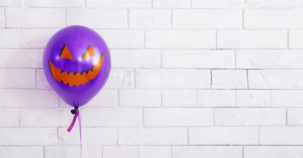 Celebrando globo púrpura con sonrisa malvada en la pared de ladrillos blancos —  Fotos de Stock
