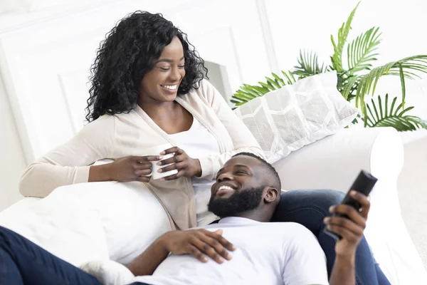 Schwarzes Familienpaar entspannt sich auf dem Sofa und verbringt Zeit zu Hause. — Stockfoto