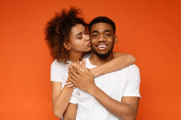 Loving black woman kissing her boyfriend from back