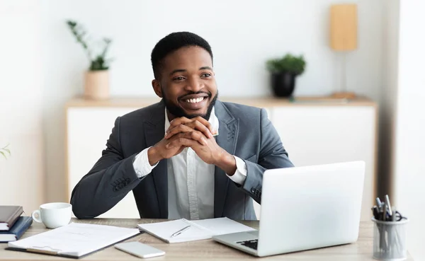 Sorrindo homem de negócios negro sonhando acordado no local de trabalho no escritório — Fotografia de Stock
