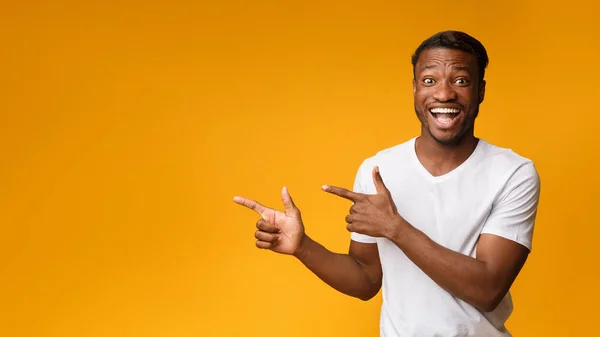 Podekscytowany African American Guy wskazując palce bok, żółte tło, Panorama — Zdjęcie stockowe