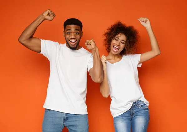 African american girl and guy enjoying success, clenching fists