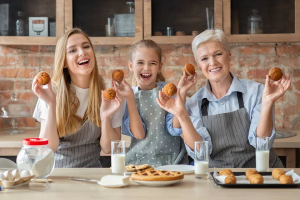 Gelukkige vrouwen die versgebakken cupcakes en glimlachend houden — Stockfoto