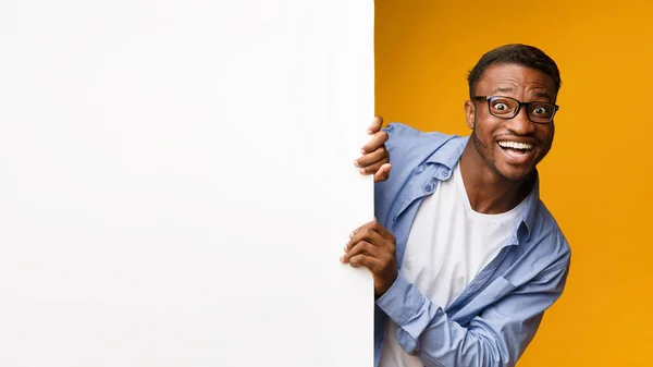 Afro man op zoek uit witte bord, gele achtergrond, mockup — Stockfoto