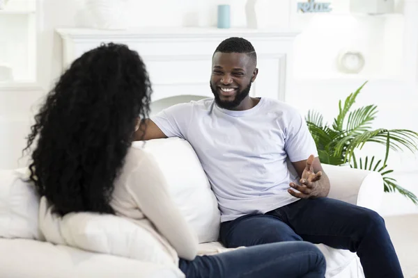Jovem casal afro conversando e descansando no sofá em casa — Fotografia de Stock