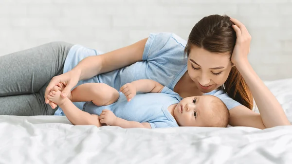 Young mother and newborn baby lying on bed at home — Stock Photo, Image