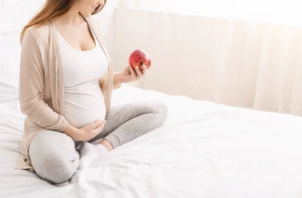 Wanita hamil muda makan apel merah di tempat tidur di rumah — Stok Foto