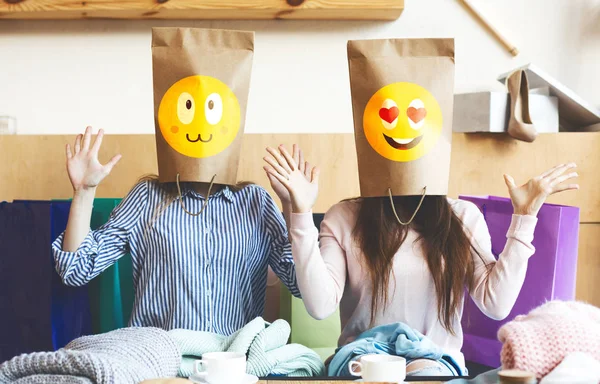 Duas meninas com sacos de papel sorridentes em vez de cabeças sentadas no café — Fotografia de Stock