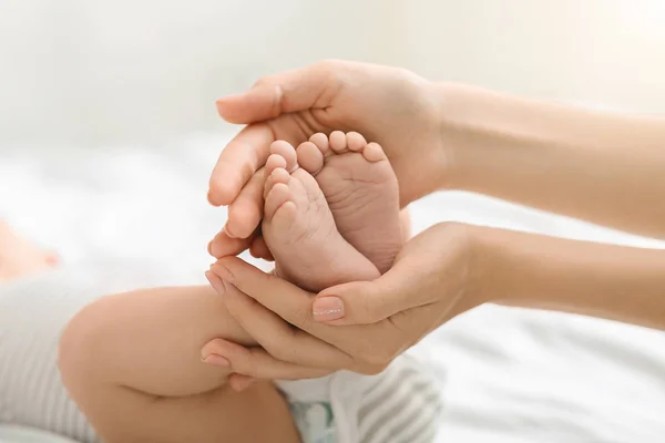 母と子供ママの手で小さな赤ちゃんの足. — ストック写真