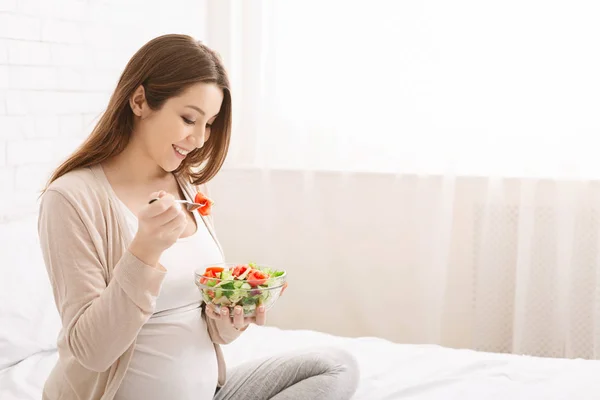Беременная женщина тысячелетия ест натуральный овощной салат — стоковое фото
