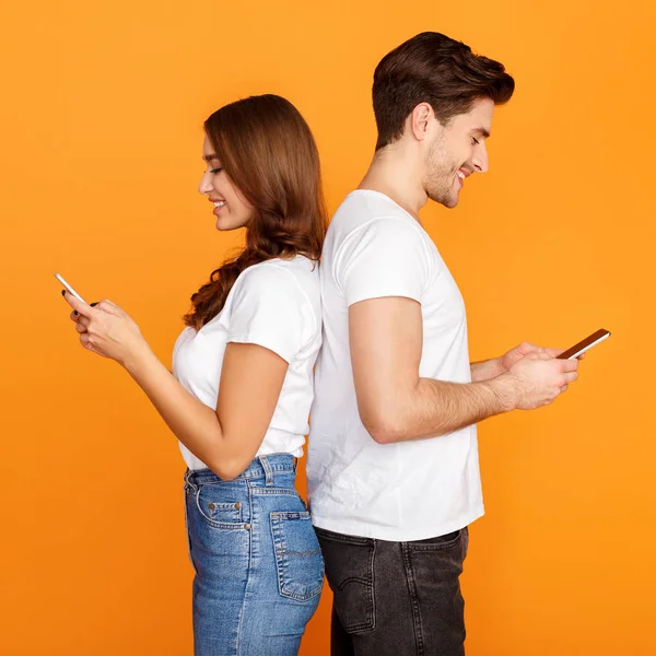 Νεαρό ζευγάρι που χρησιμοποιεί κινητά, στέκεται πίσω στο πίσω μέρος — Φωτογραφία Αρχείου
