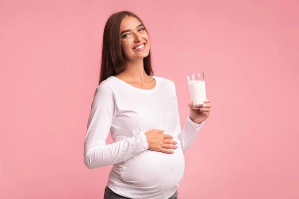 Wanita hamil Memegang Kaca Dari Susu Berdiri Atas Latar Belakang Merah Muda — Stok Foto