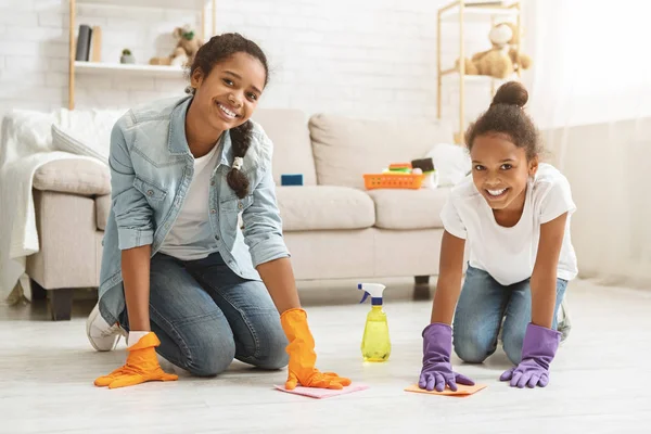 Две очаровательные девушки чистят ковер дома — стоковое фото