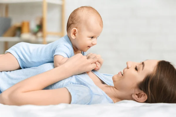 Porträtt av bedårande bebis leker med sin mor i sängen — Stockfoto