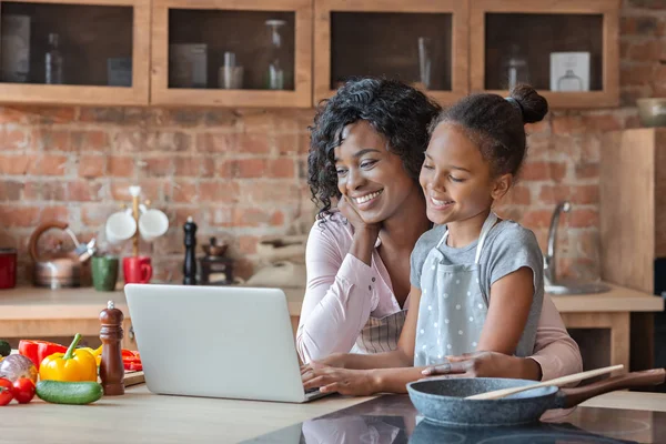 Mamá y su hija leyendo receta en el ordenador portátil en la cocina — Foto de Stock